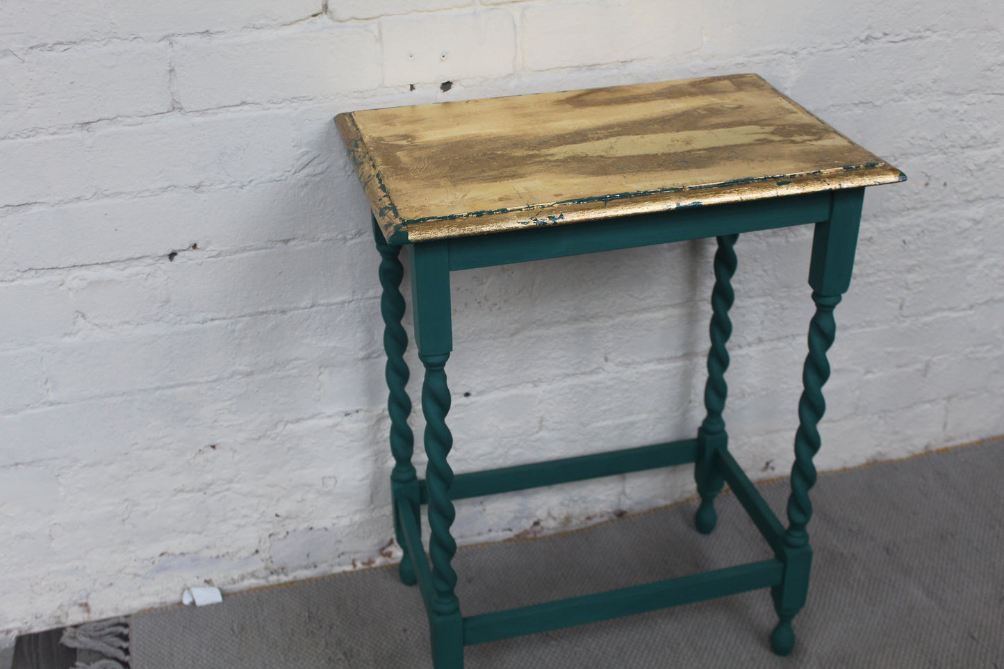Green table with barley twist legs that has a gold leaf finished gloss top